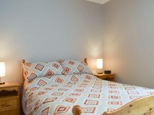 a bed with a blanket and two lamps on two tables at The Barn in Fintry +7 photos