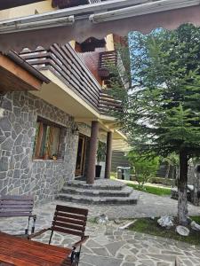 une maison avec un banc et un arbre devant elle dans l'établissement Casa Yna, à Buşteni 21 autres photos