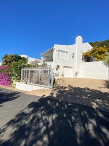 une maison blanche avec une clôture blanche et des fleurs dans l'établissement Garden cottage, à Plettenberg Bay