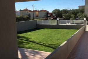 a yard of grass on the side of a fence at 2 Bed-Sleeps4-Garden-Parking-Pets-AirCon in Nikiti +8 photos