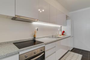 Una cocina con gabinetes blancos y un fregadero. en Atlantic Dutchman, en Caniço