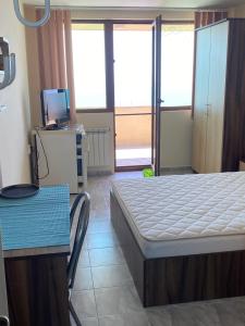 a bedroom with a bed and a table and a television at Стаи за гости Денкови in Burgas City