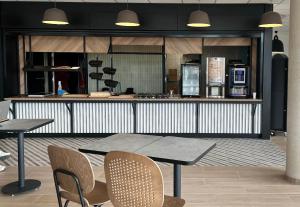 a kitchen with two tables and chairs and a counter at B&B HOTEL Moulins Avermes in Avermes