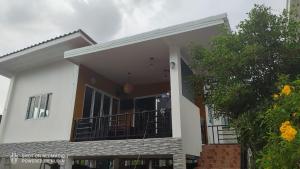 a white house with a balcony and a tree at Green moonVillage in Ban Nok