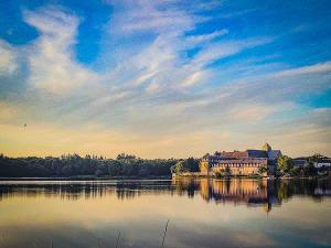 a large building sitting on top of a large lake at La Maison en Brocéliande in Paimpont
