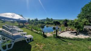 a row of lounge chairs with an umbrella and a pond at Calla Retreat in Vezenkovo