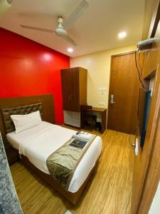 Un dormitorio con una cama y una pared roja. en Arton By Hotel Avion Palace, en Bombay
