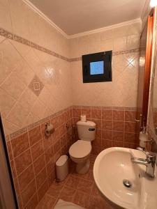 a bathroom with a toilet and a tv on the wall at Naos Family House , Paralia Ofriniou in Ofrínion