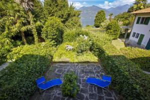 Dos sillas azules sentadas en un camino de piedra en un jardín. en Casa Magnolia, en Luino