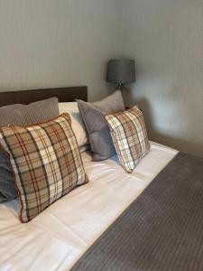 a bed with three pillows on it with a lamp at The Crescent in Dundee