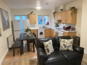 a living room with a black leather couch and a kitchen at Super Central Location Private Room 1 in Dublin