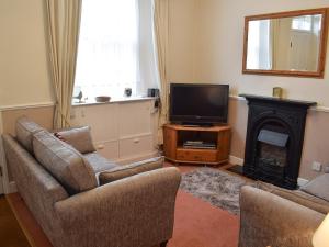 sala de estar con TV y chimenea en Pear Tree Cottage, en Bowness-on-Windermere