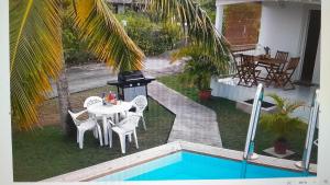a backyard with a table and chairs and a grill at Embruns 2 in Le Moule