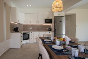 Una cocina con una mesa de madera y gabinetes blancos. en Sanctuary Beach Villas by "Elite", en Alikanas