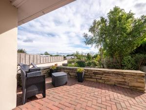 un patio con due sedie e un muro di pietra di One bedroom bungalow with private garden at Parkland, near Kingsbridge a Kingsbridge
