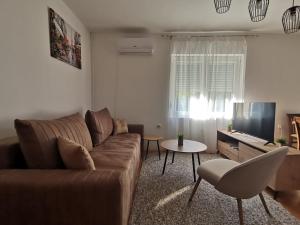 ein Wohnzimmer mit einem braunen Sofa und einem Tisch in der Unterkunft Apartman Pače in Raška