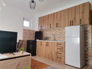 eine Küche mit Holzschränken und einem weißen Kühlschrank in der Unterkunft Apartman Pače in Raška