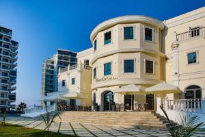 ein großes weißes Gebäude mit Sonnenschirmen davor in der Unterkunft Caesar Resort & Spa Luxury Apartments in Iskele