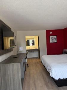 a hotel room with a bed and a desk with a television at Travelodge by Wyndham Lumberton in Lumberton