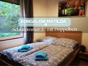 a bed with two blue pillows on top of it at Bungalow Matilda in Lauchhammer