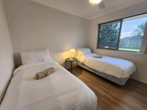 a bedroom with two beds and a window at Simple and Comfy Family Home between BNE and Ipswich in Bellbird Park