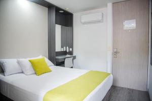 a bedroom with a large white bed with a yellow pillow at Eco Star Hotel in Ibagué