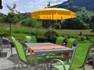 a table and chairs with a yellow umbrella at Apartment Alpenchalet Spiher Parterre by Interhome in Gstaad