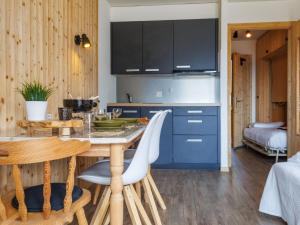 a kitchen with blue cabinets and a table and chairs at Studio Beau Soleil G11 by Interhome in Veysonnaz