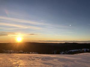 a sunset from the top of a snow covered slope at Holiday Home Black Forest Hideaway by Interhome in Falkau