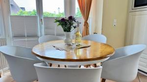 a dining room table with white chairs and a vase with flowers at Syltrose Whg 1a in Westerland (Sylt)