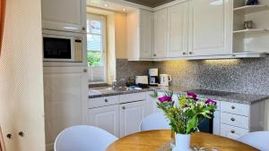 a kitchen with white cabinets and a wooden table with flowers at Syltrose Whg 1a in Westerland (Sylt) +34 photos