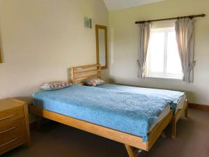 a bedroom with a wooden bed and a window at Brankley Cottage - E4712 in Dunstall