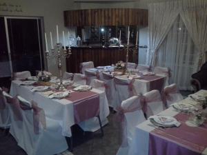 een groep tafels met witte tafelkleden en bogen bij De Zevende Hemel Guesthouse in Secunda
