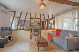 a living room with a couch and a tv at Gîte Marotte - Climatisé avec Jardin in Beaumont-en-Beine