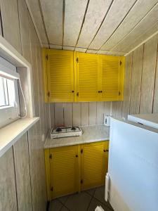 a kitchen with yellow cabinets and a white refrigerator at Holiday - domek letniskowy 2 in Charzykowy +12 photos