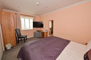 Un dormitorio con una cama, un escritorio y un televisor. en Lyme Bay House, en Dawlish