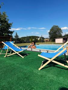 a man sitting in a swimming pool with two lounge chairs at Holiday - domek letniskowy 2 in Charzykowy