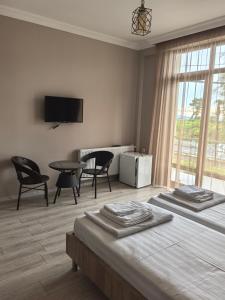 una camera da letto con due letti, un tavolo e delle sedie di FRESH Hotel Kobuleti a Kobuleti Altre 37 foto