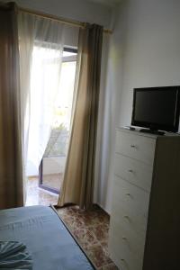 a bedroom with a dresser with a tv and a window at Hotel President in Golem