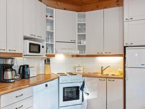 une cuisine avec des armoires blanches et des appareils électroménagers blancs dans l'établissement Holiday Home Karhu by Interhome, à Savonranta