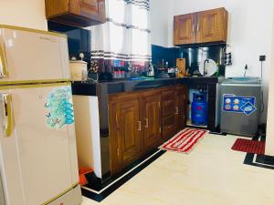 a kitchen with wooden cabinets and a white refrigerator at Rest N surf Apartments in Ahangama