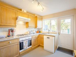 a kitchen with wooden cabinets and a white stove top oven at Russell Cottage in Alnwick