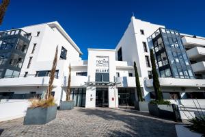 Un edificio blanco con árboles delante. en Nemea Appart Hotel Les Hauts de Milady Biarritz, en Biarritz