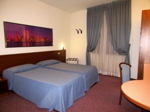 プラートにあるホテル ジャルディーノのベッドと大きな窓が備わるホテルルームです。