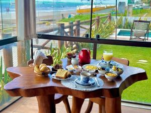 a wooden table with breakfast food on a balcony at Pousada Ecohar Yoga in Maragogi