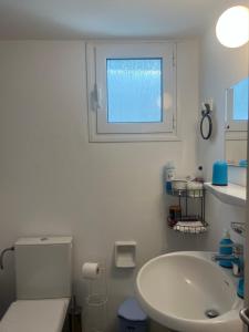 a bathroom with a sink and a toilet and a window at Cozy house by the sea in Batsi