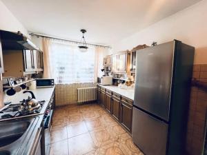 a kitchen with a stainless steel refrigerator and a sink at Stylish 4BR Artist's Home with Garden- Gdańsk Green District by AVALON ATELIER in Gdańsk