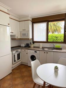 ウスルビルにあるApartamento con jardin y parking privadoの白いキャビネットとテーブルと窓のあるキッチン +3枚の写真