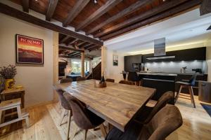 a kitchen and dining room with a wooden table and chairs at Casa Montlude - Elegancia rústica y confort moderno en el corazón del Valle de Arán by Eth Flòc in Gessa