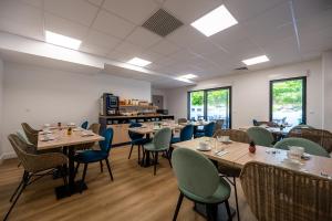 a dining room with tables and chairs and windows at Nemea Appart Hotel Les Hauts de Milady Biarritz in Biarritz